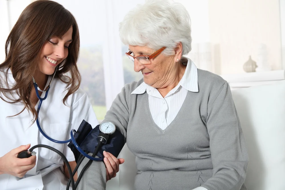 Skilled nurse checking an older woman's blood pressure at home